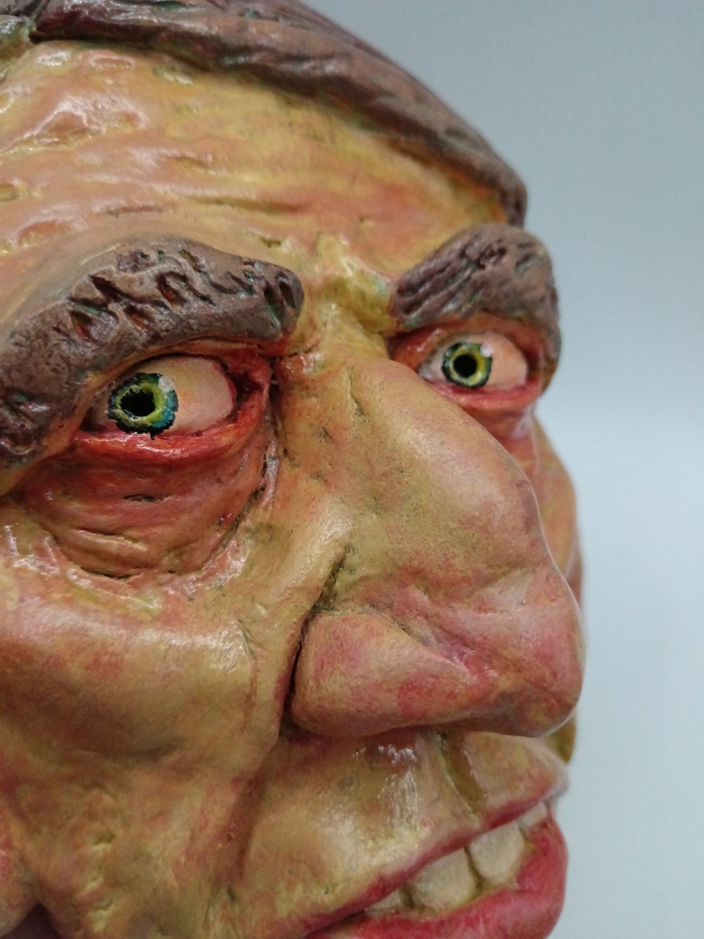 Hand sculpted clay yellow face mask sculpture close-up