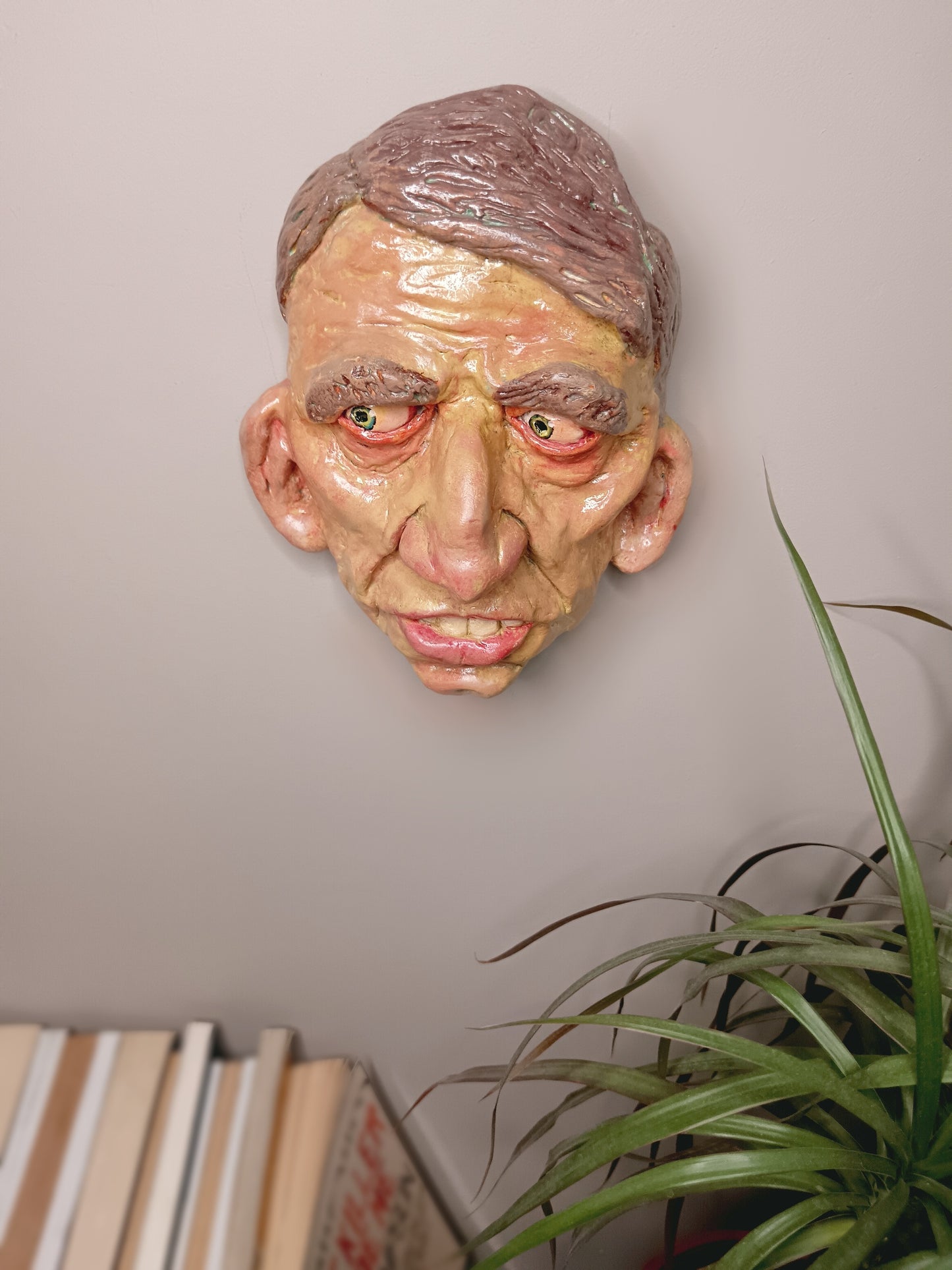 Hand sculpted clay yellow face mask sculpture top view wall art