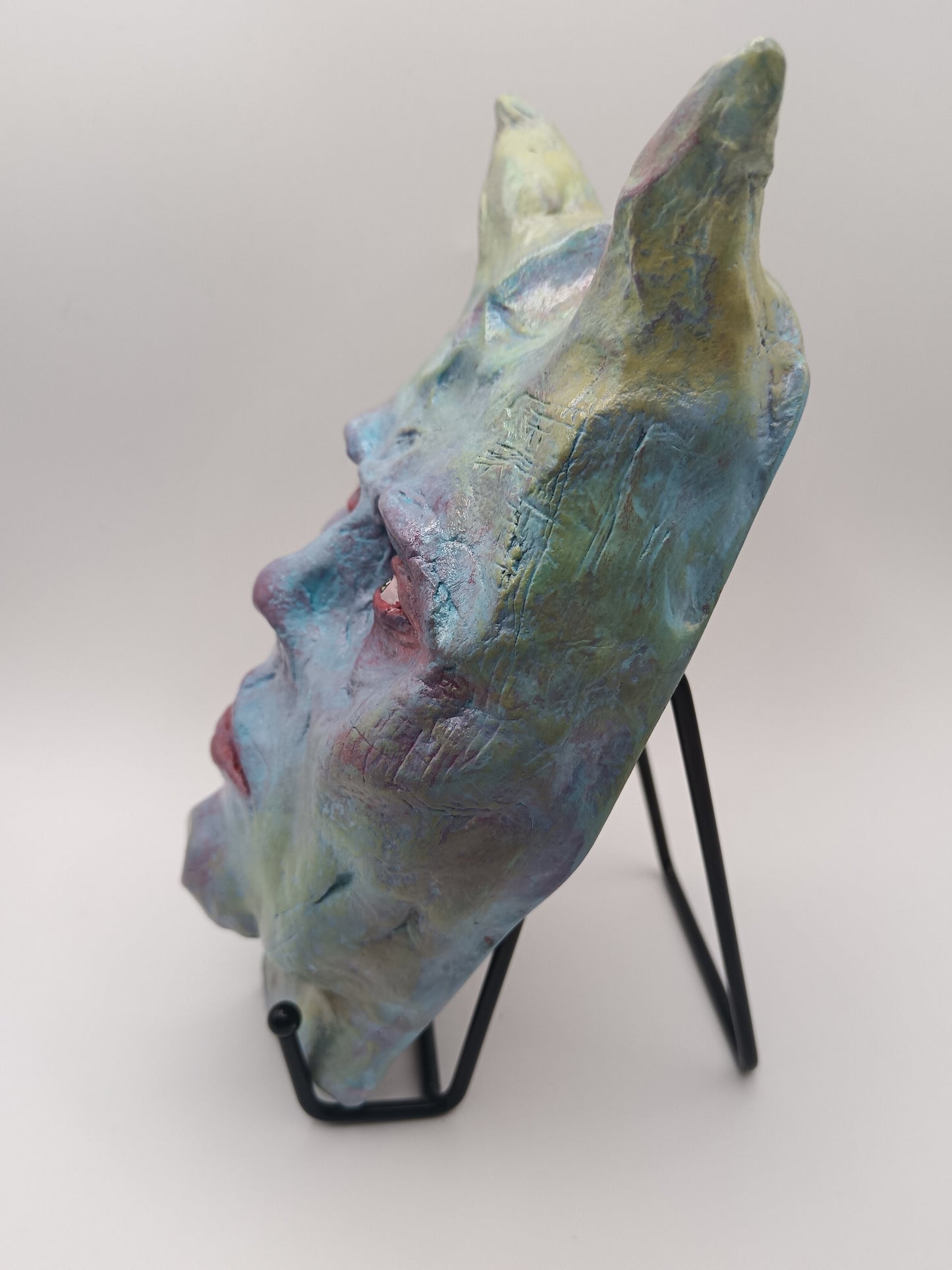 Hand sculpted clay pastel demon sculpture withs stand left view