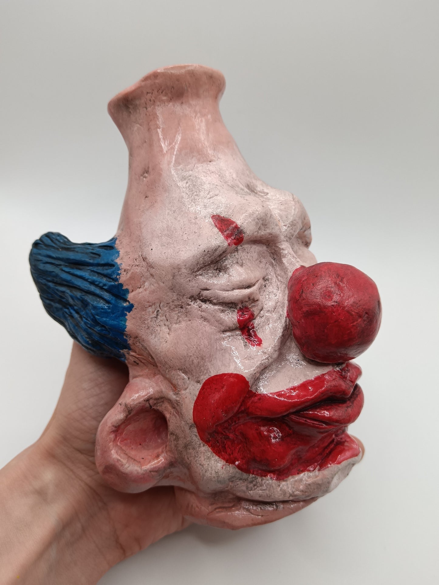 Handmade clay clown vases with blue hair in hand