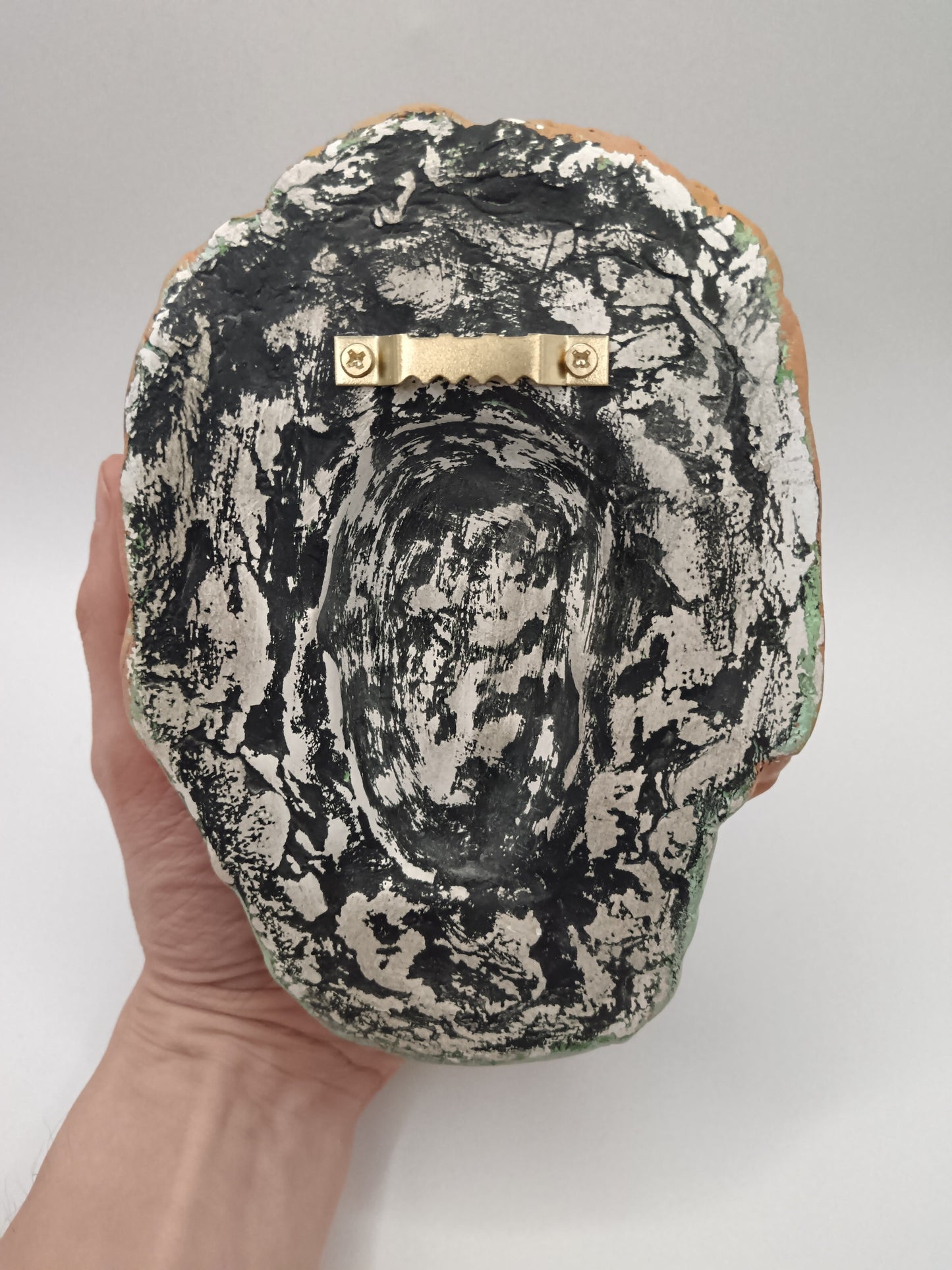 Back of mask sculpture with sawtooth hanger on back