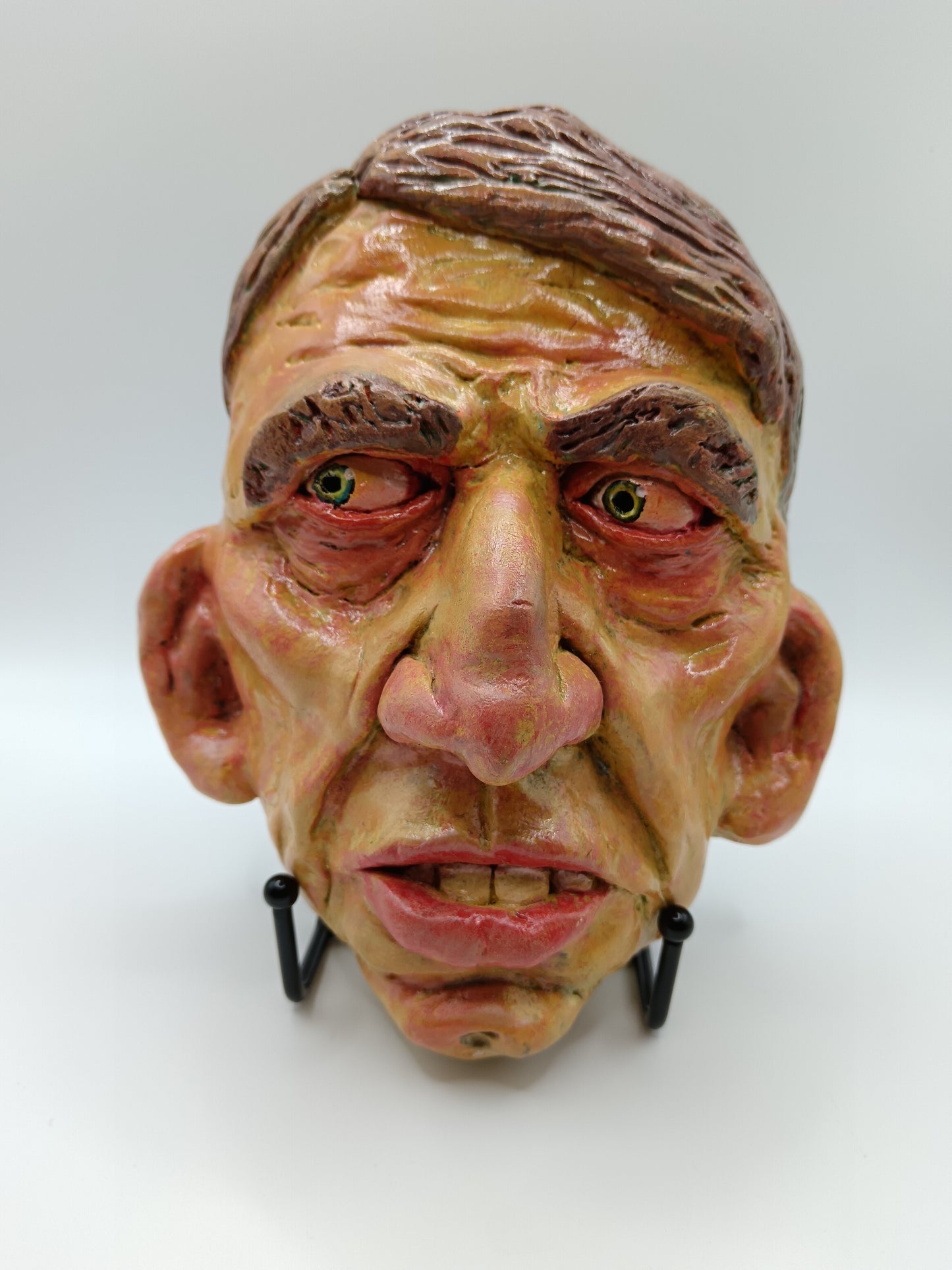 Hand sculpted clay yellow face mask sculpture with stand front