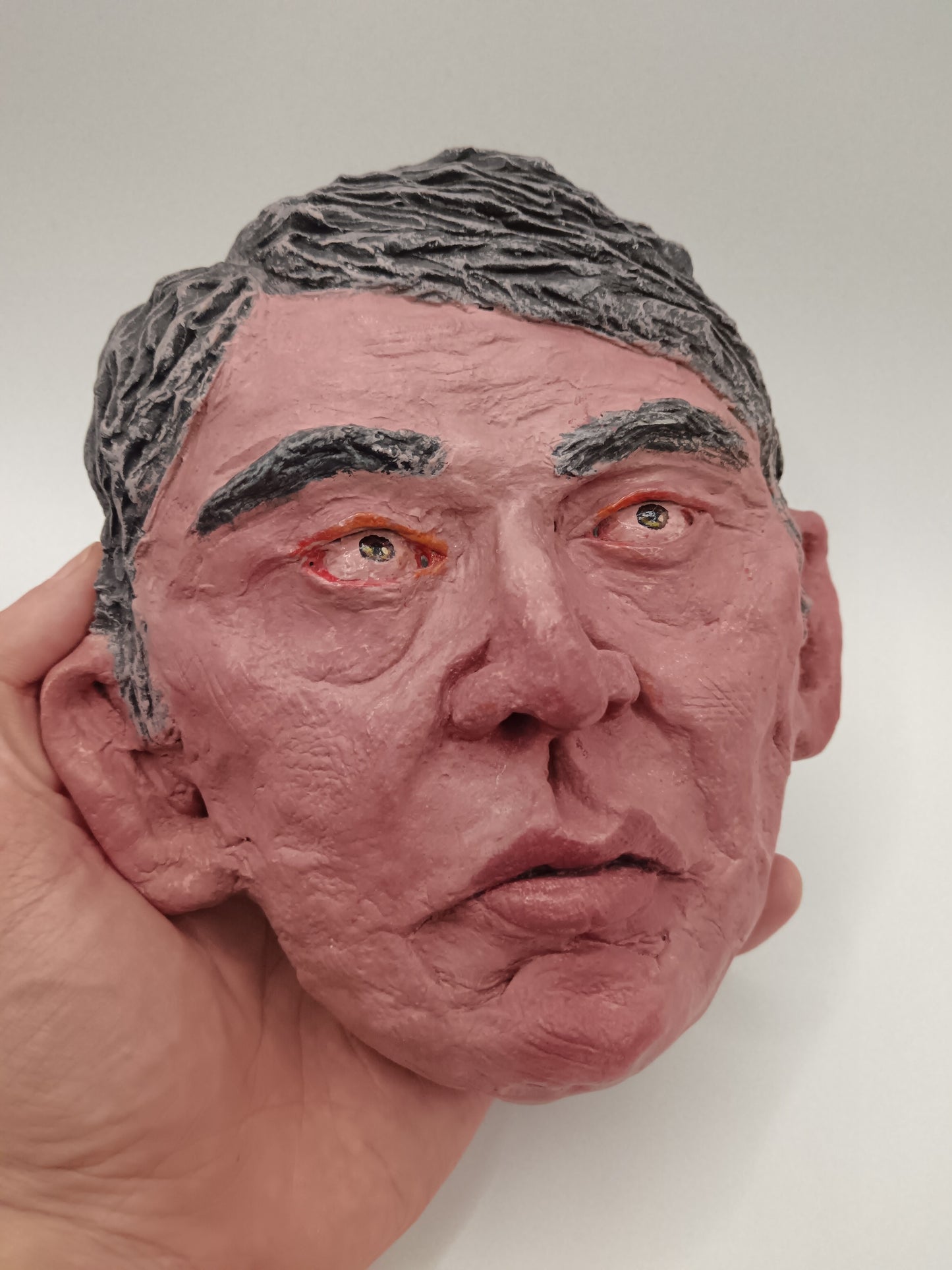 Close-up of a detailed sculpture of a human head with gray hair.