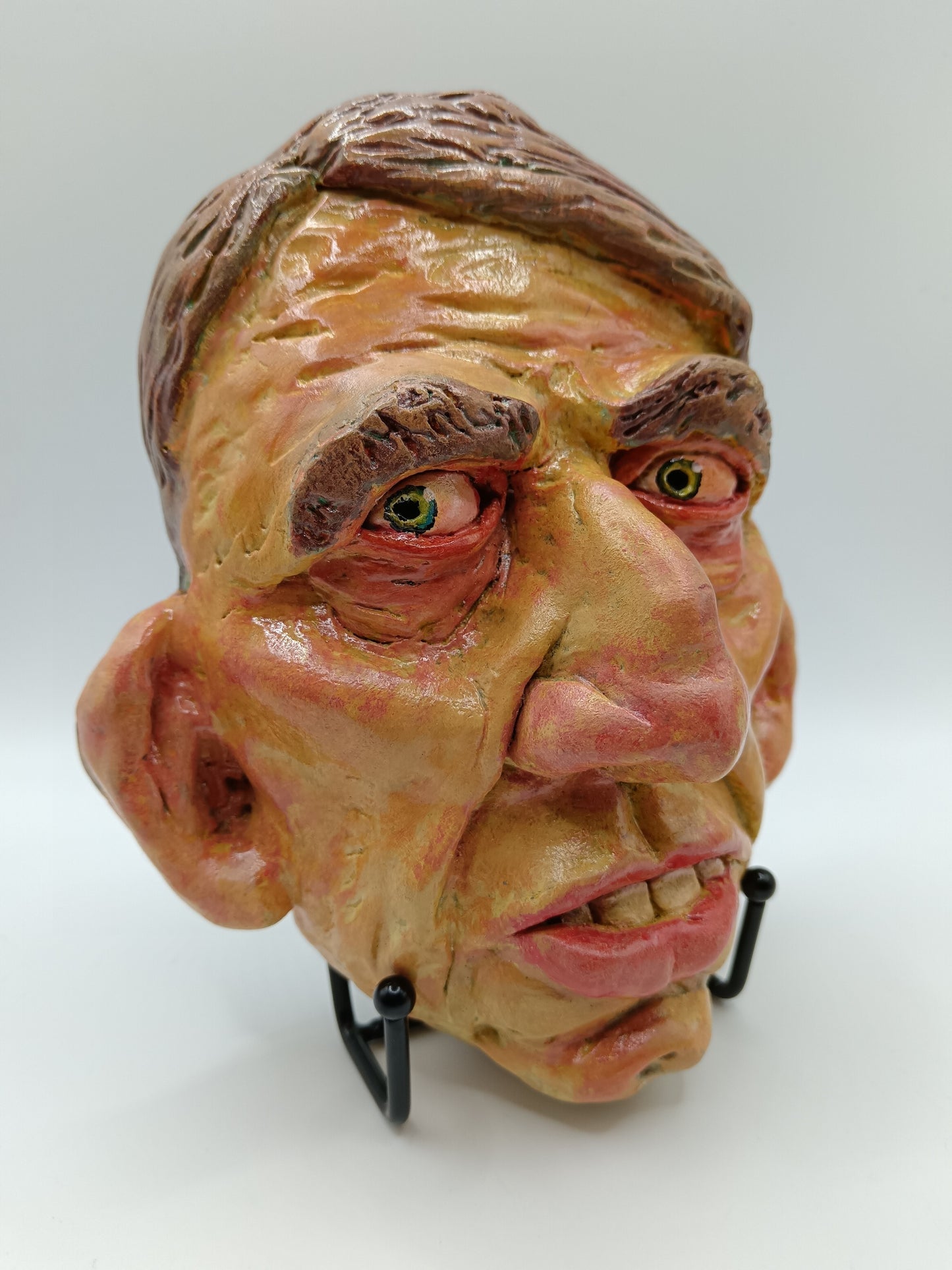 Hand sculpted clay yellow face mask sculpture with stand front right