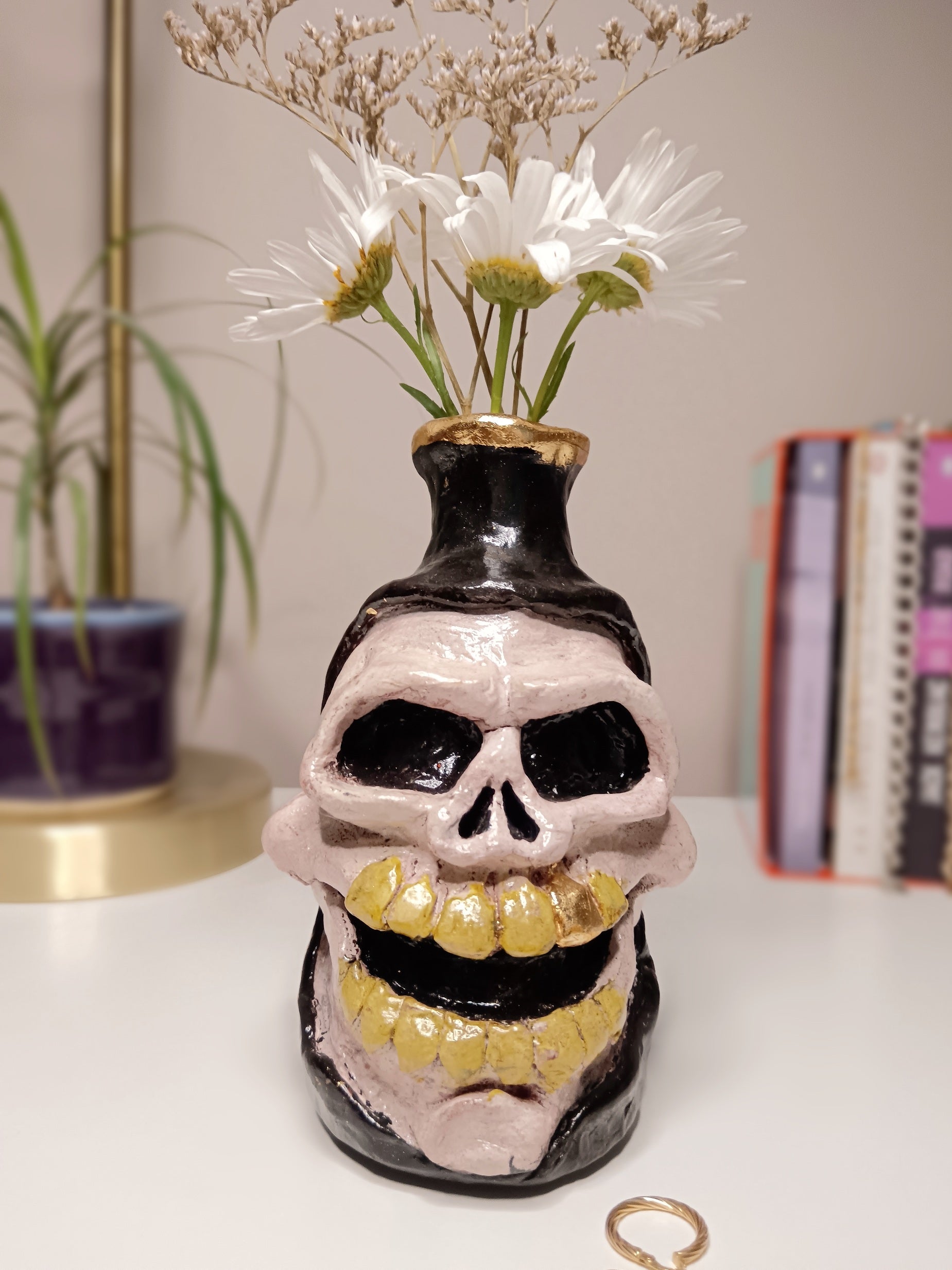 Skull-shaped vase with yellow teeth on a white surface, home setting