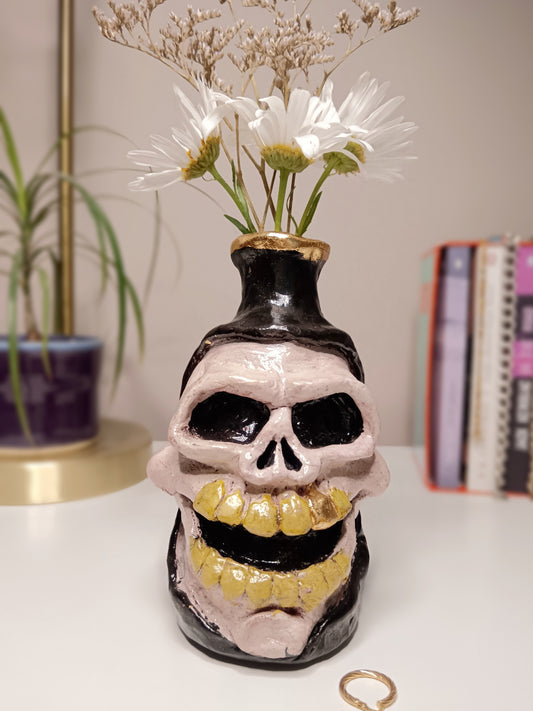 Skull-shaped vase with yellow teeth on a white surface, home setting