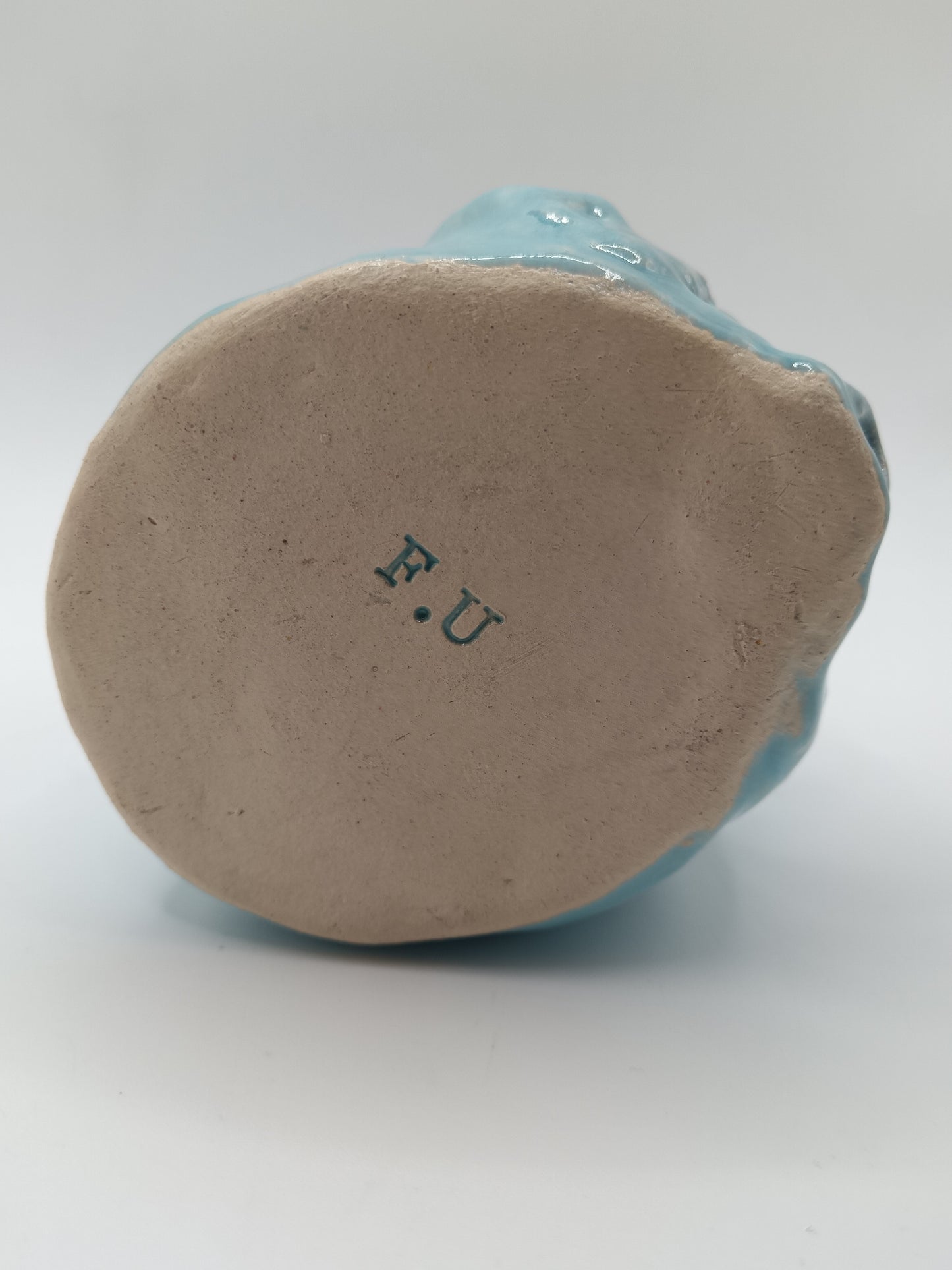 Ceramic figurine with 'F.U.' marking on a white background