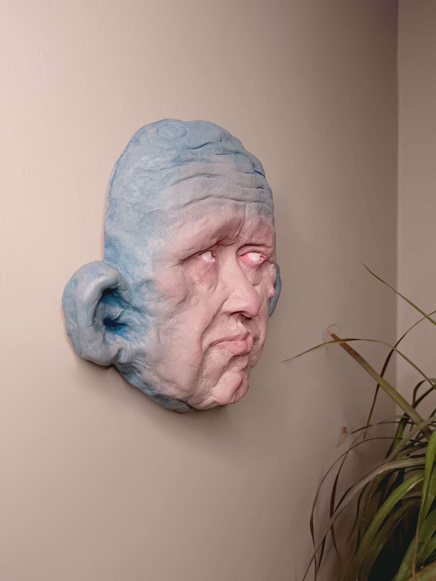 Blue face Handmade sculpture on stand, wall mounted side view