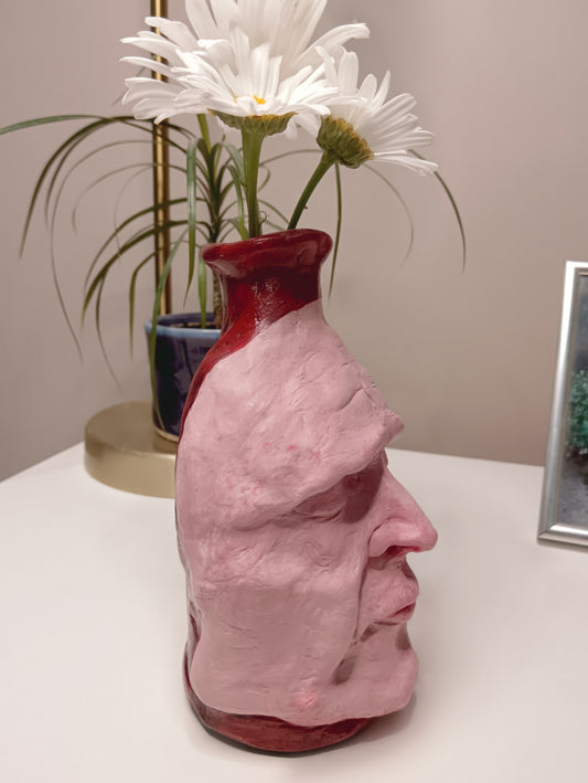 Handmade clay death mask vase, with flowers, side
