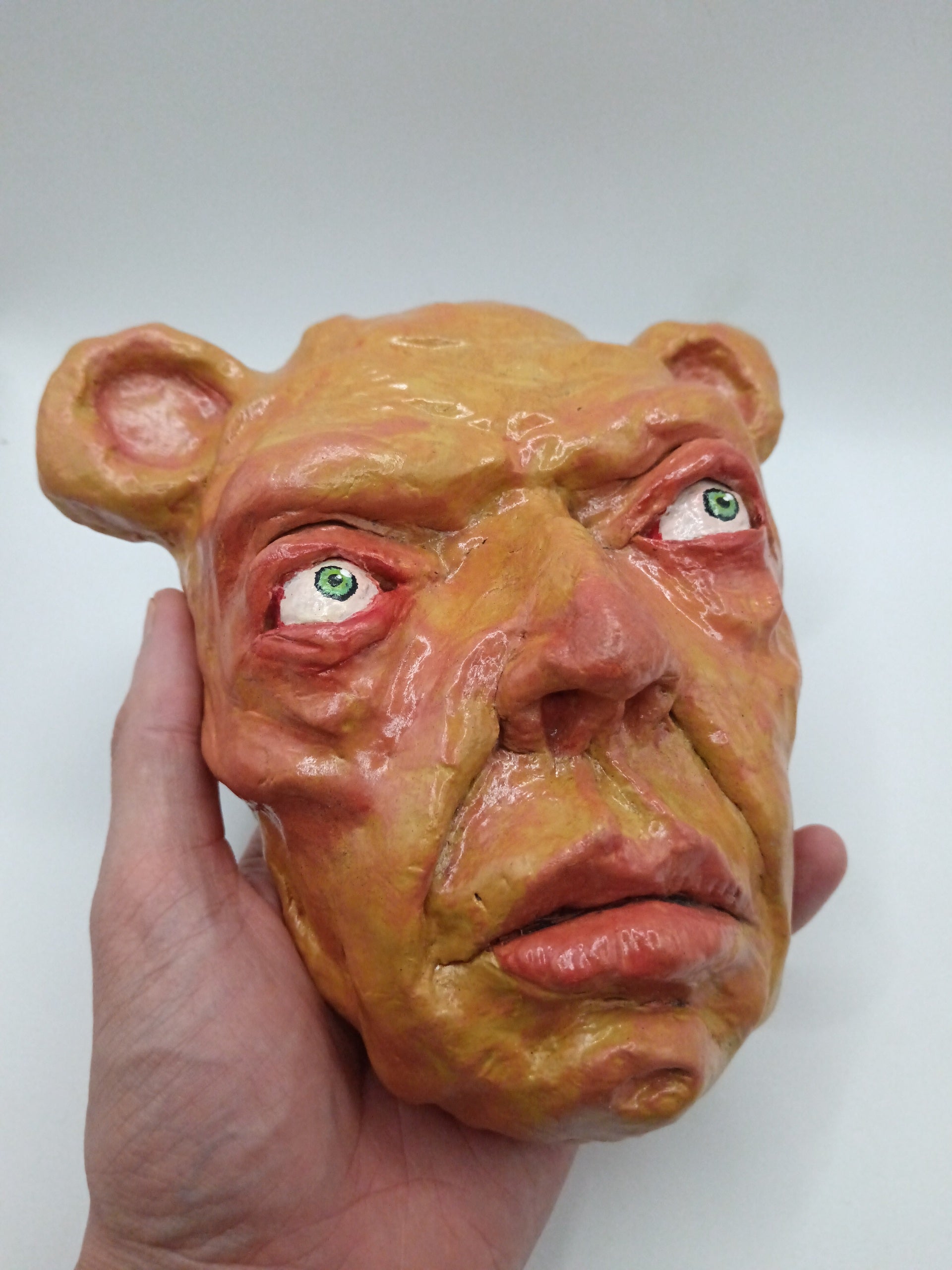 Hand holding a mask with a distorted face on a white background
