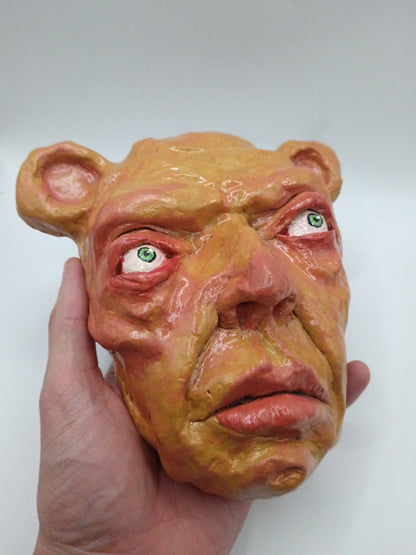 Hand holding a mask with a distorted face on a white background