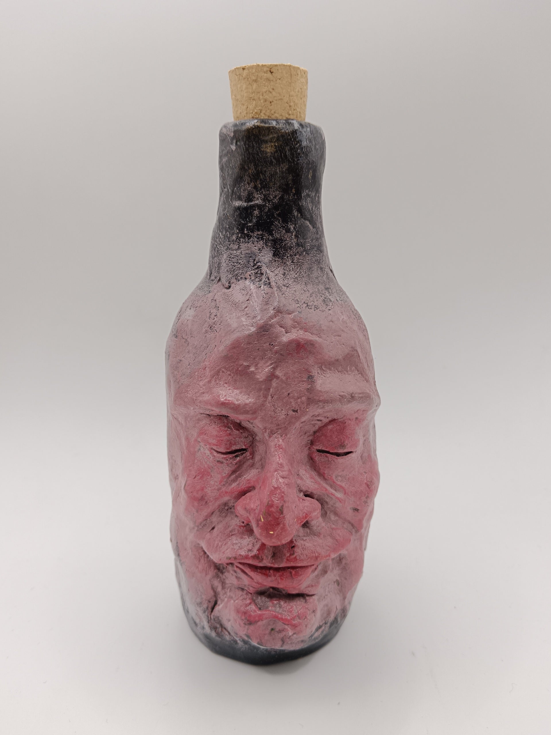 Bottle shaped like a face with a cork on a white background