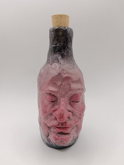 Bottle shaped like a face with a cork on a white background