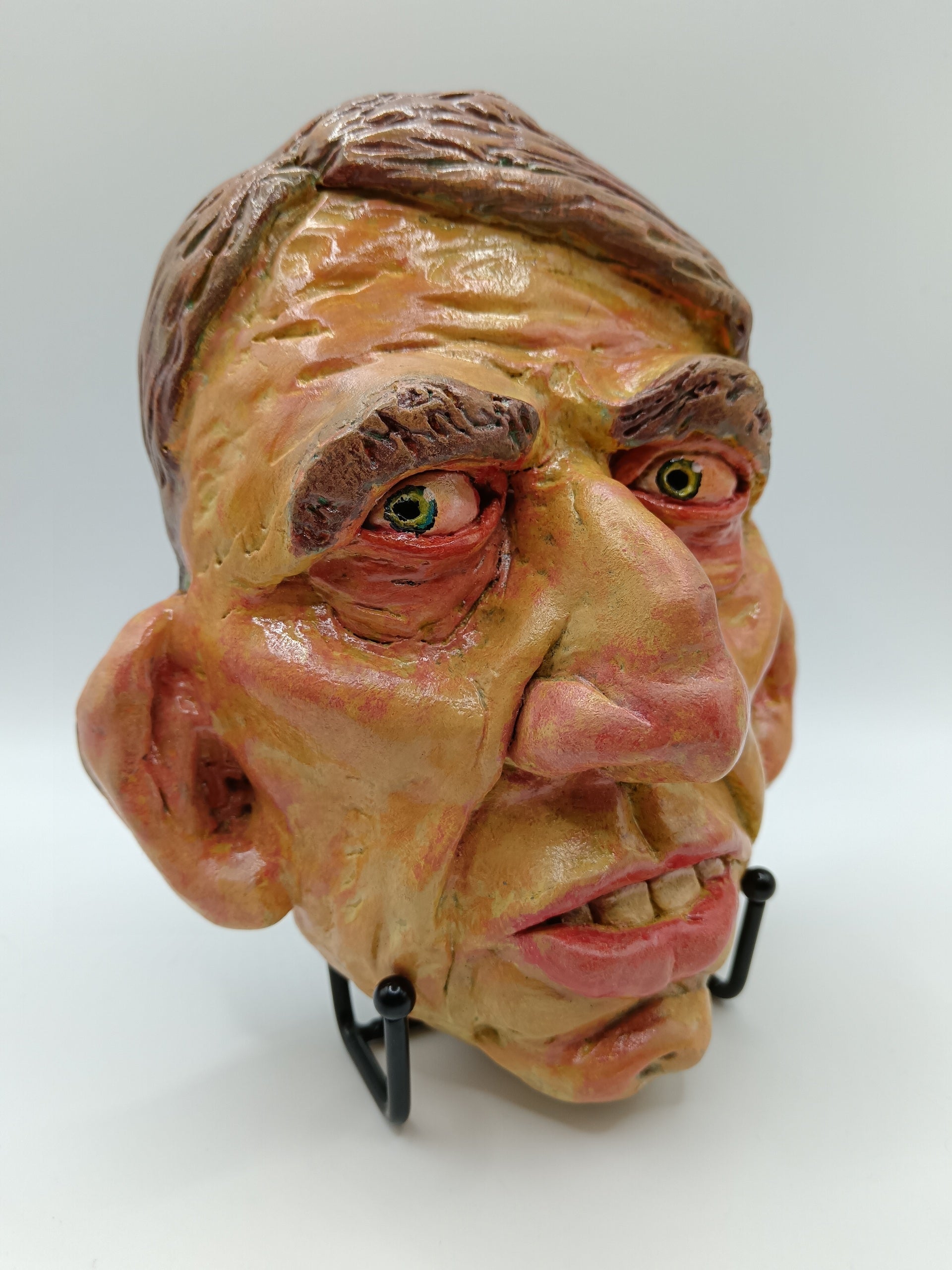 Hand sculpted clay yellow face mask sculpture with stand front right