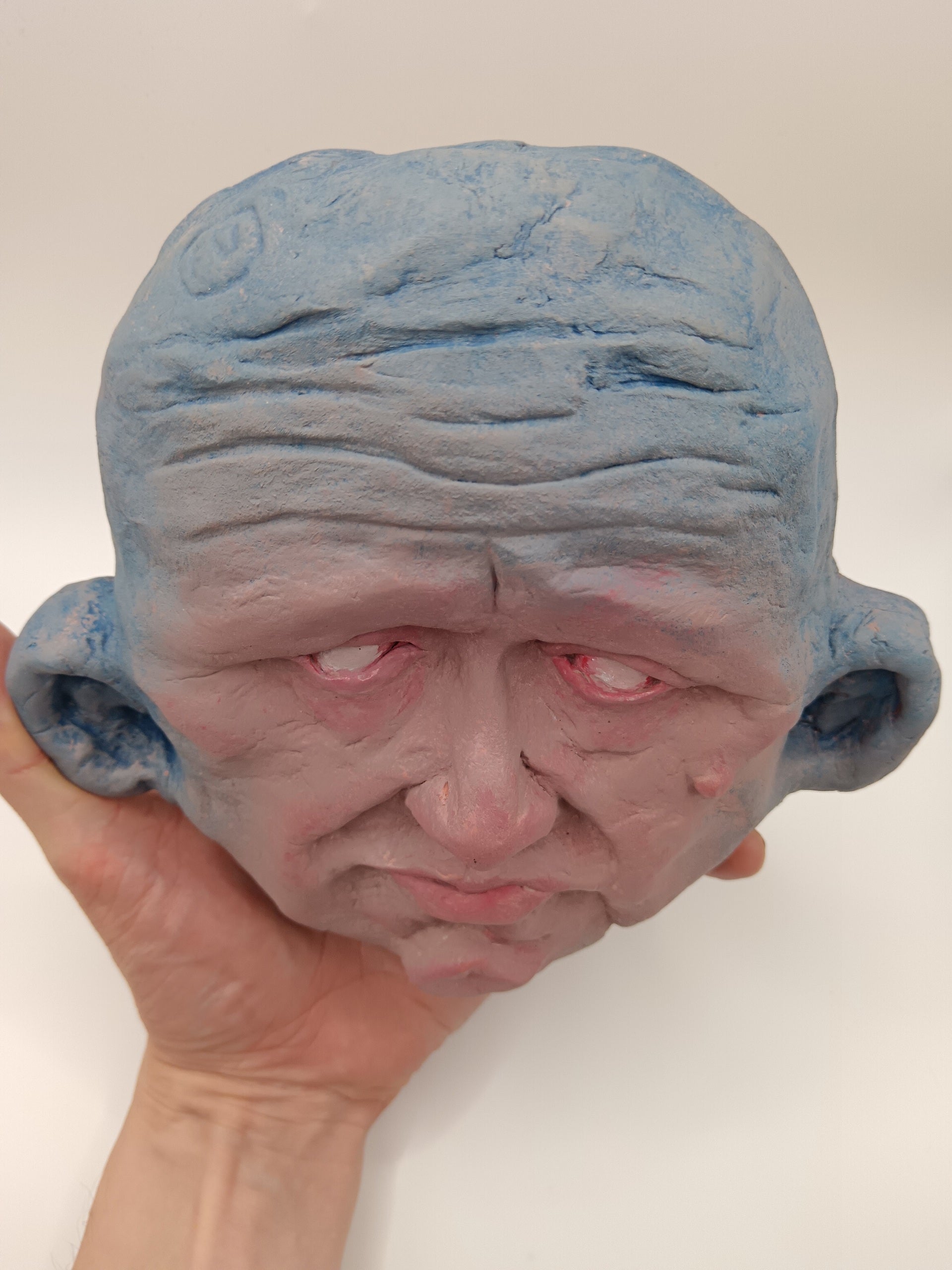 Blue mask with a textured surface held by a hand against a plain background